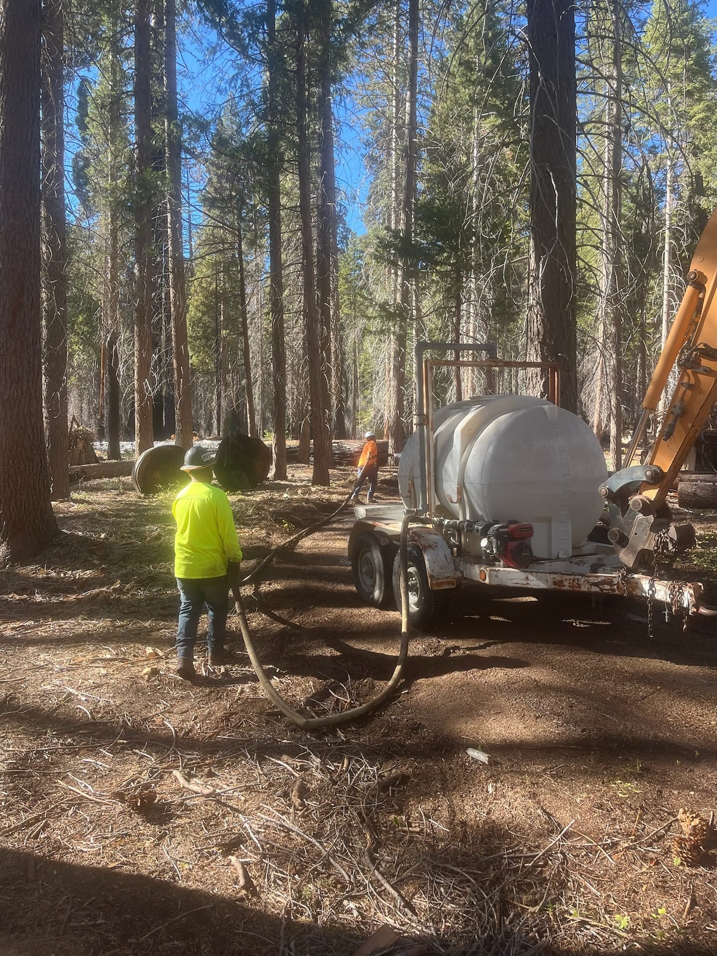 Crew running a water trailer for dust control on a forest jobsite